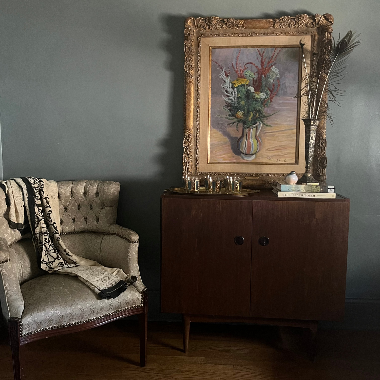 Vintage armchair and sideboard with decorative items against a gray wall